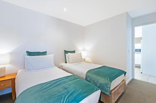 two beds in a room with a window at The Victoria Apartments in Port Fairy
