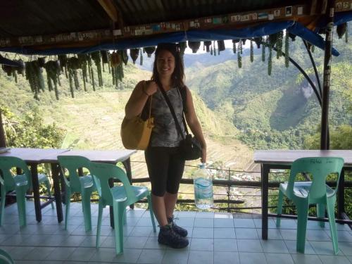 a woman standing in front of a table and chairs at BATAD Rita's Mount View Inn and Restaurant in Banaue