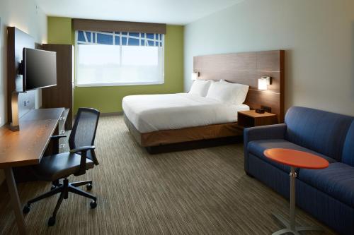 Holiday Inn Express & Suites - Cincinnati North - Liberty Way, an IHG Hotel في ويست تشيستر: غرفة الفندق بسرير ومكتب واريكة