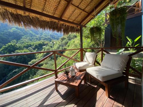 a balcony with two chairs and a table and a view at Reserva Natural Tierra Adentro in Minca