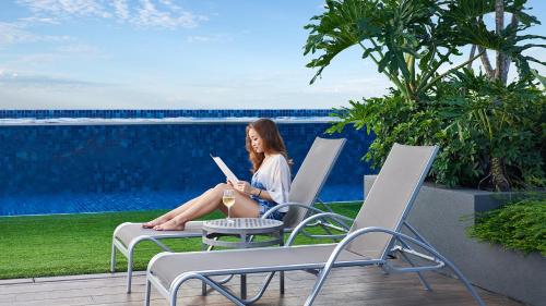 a woman sitting in lawn chairs reading a book at Holiday Inn Express Singapore Clarke Quay by IHG in Singapore