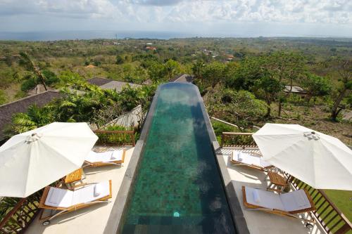 una piscina con sillas y sombrillas en un complejo en Villa Ali Agung, en Uluwatu
