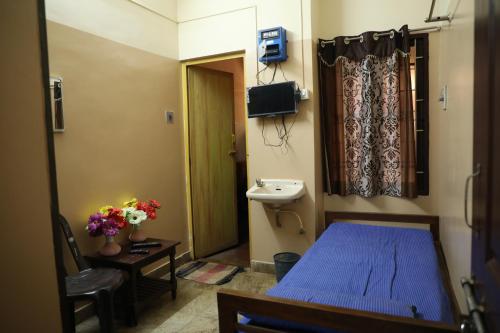 ein Schlafzimmer mit einem blauen Bett, einem Waschbecken und einem Fenster in der Unterkunft R. VE. R Residency in Thanjavur