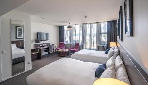 Habitación de hotel con 2 camas y escritorio en Scenic Hotel Dunedin City en Dunedin