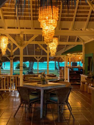 a dining room with a table and chairs and chandeliers at El Mosquito Boutique Hotel Playa Bonita in Las Terrenas