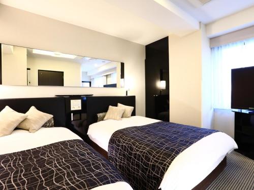 a hotel room with two beds and a mirror at APA Hotel Ginza Shintomicho Ekimae in Tokyo