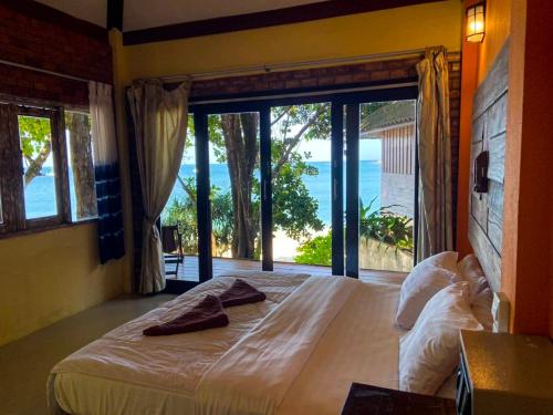 a bedroom with a bed with a view of the ocean at Chomjan Resort in Ko Phayam