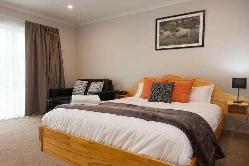 a bedroom with a large bed with orange and black pillows at Otorohanga & Waitomo Motels in Otorohanga