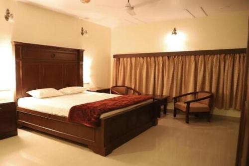 a bedroom with a bed and a chair and a window at karnavati Retreat in Panna