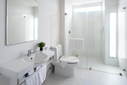 a white bathroom with a toilet and a sink and a shower at Eco Inn Prime Mae Sot in Mae Sot