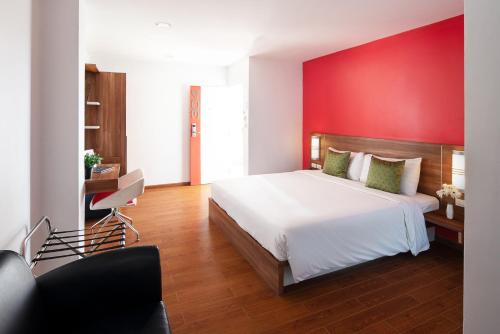 1 dormitorio con 1 cama grande y pared roja en Eco Inn Prime Mae Sot, en Mae Sot