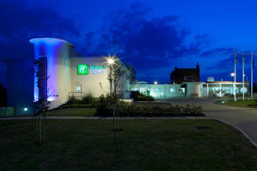 a building with a lit up sign at night at Holiday Inn Express Ramsgate – Minster by IHG in Ramsgate