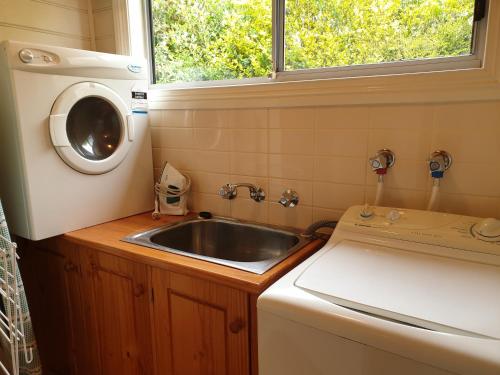 una pequeña cocina con fregadero y lavadora en Belle Cottage en Scottsdale