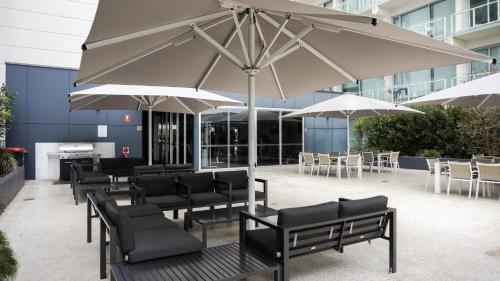 a patio with tables and chairs and umbrellas at Tasha's Apartments on Warwick in Adelaide