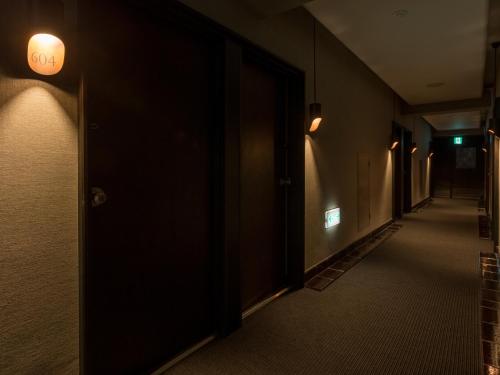 an empty hallway with a door and lights on the wall at THE HOTELS HAKATA KASANE Bayside in Fukuoka