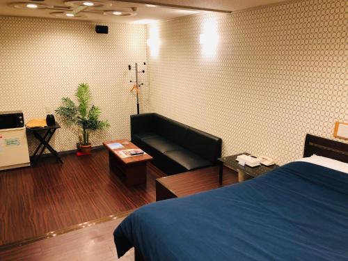 Habitación de hotel con cama y sofá en Hotel Mermaid (Leisure Hotel) en Beppu