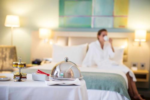 a woman sitting on a bed talking on a cell phone at Holiday Inn Mauritius Mon Trésor by IHG in Blue Bay