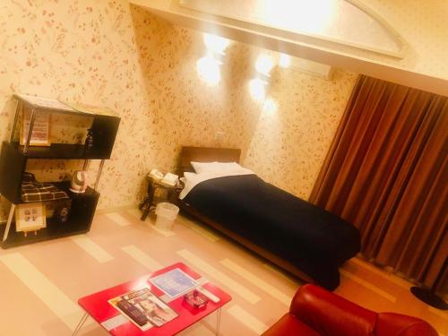 małą sypialnię z łóżkiem i czerwoną kanapą w obiekcie Hotel Mermaid (Leisure Hotel) w mieście Beppu