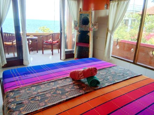 a bed with a red object on top of it at Pelangi Beach Homestay in Amed