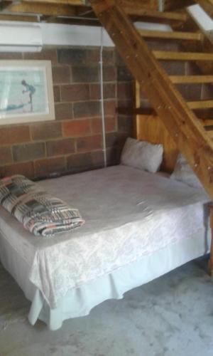 a bed in a room with a brick wall at Lothian rd Cottage in Durban