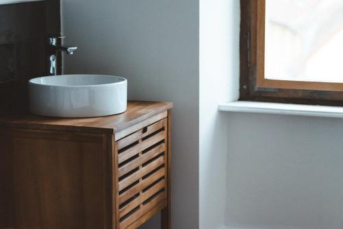 a bathroom with a sink on top of a wooden dresser at Sojolidays - Appartements d'hôtes sur la Route des Vins d'Alsace in Rorschwihr