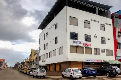 a white building with cars parked in front of it at Treebo Shivani in Indore