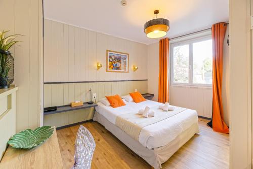 a bedroom with a large white bed with orange pillows at Hotel Cote Basque in Bayonne