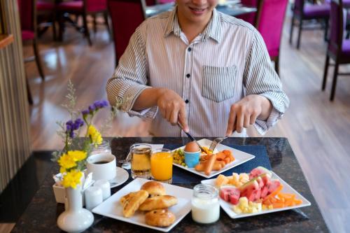 Ein Mann, der an einem Tisch mit einem Tablett Essen sitzt. in der Unterkunft Novotel Phuket Vintage Park Resort in Patong Beach