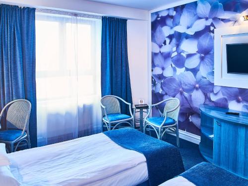 um quarto de hotel com uma cama e cadeiras e uma televisão em Continental Forum Tirgu Mures em Târgu-Mureş