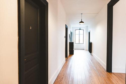 a hallway with white walls and a black door at Sojolidays - Appartements d'hôtes sur la Route des Vins d'Alsace in Rorschwihr
