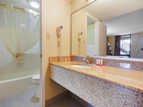 ein Badezimmer mit einem Waschbecken, einem WC und einem Spiegel in der Unterkunft Baymont by Wyndham Williamsburg in Williamsburg