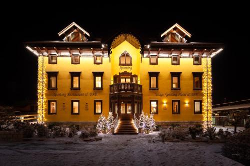 a large yellow building with christmas lights in front of it at Asiago Sporting Hotel & Spa in Asiago