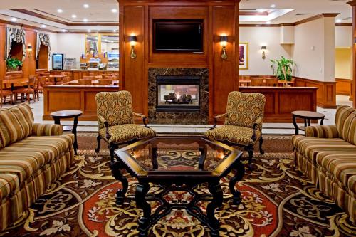 a lobby with a fireplace and couches and a table at Rockville Centre Hotel - JFK Airport in Lynbrook