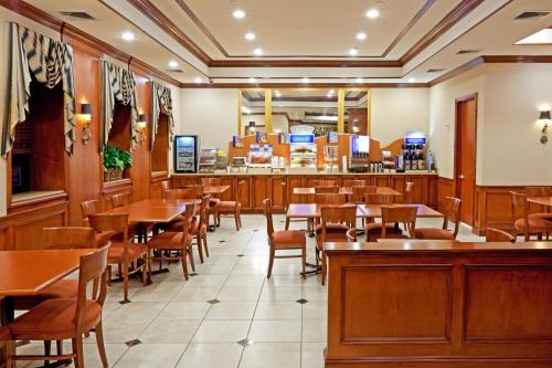 a restaurant with tables and chairs and a bar at Rockville Centre Hotel - JFK Airport in Lynbrook
