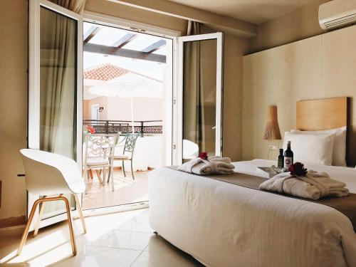 a bedroom with a large bed and a balcony at Alexandra Beach Hotel in Nea Kydonia