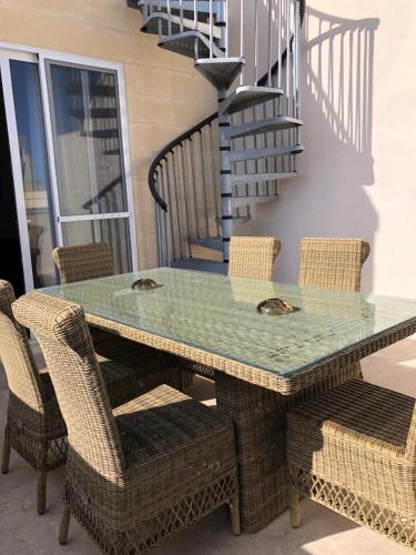 a table with wicker chairs and a green table top at Holiday townhouse in Sliema centre in Sliema
