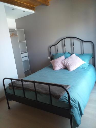 Schlafzimmer mit einem Bett mit blauer Bettwäsche und Kissen in der Unterkunft Gîte Terre in Saint-Laurent-de-Médoc