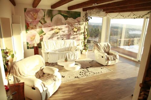a living room with white chairs and a large window at Komfortowy Dom w Chmurach in Dydnia