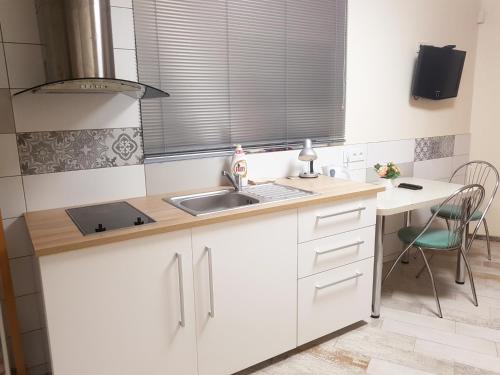 a kitchen with white cabinets and a sink and a table at Studio by the Lake Kaunas in Kaunas