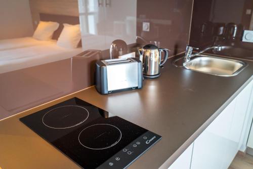 a kitchen with a counter top with a stove and a sink at All Suites Appart Hôtel - Choisy-le-Roi in Choisy-le-Roi