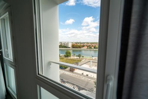 a window with a view of a river and a city at All Suites Appart Hôtel - Choisy-le-Roi in Choisy-le-Roi