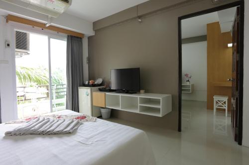 a bedroom with a white bed and a tv at Beerapan Hotel in Bangkok