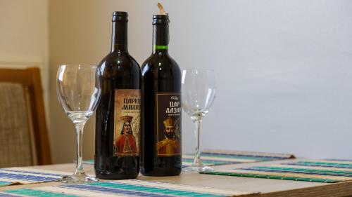 due bottiglie di vino sedute su un tavolo con due bicchieri di Apartman's Ana Pale-OC Jahorina a Pale