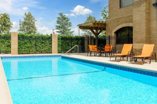 a swimming pool with chairs and a table and chairs at Holiday Inn Charlotte University, an IHG Hotel in Charlotte