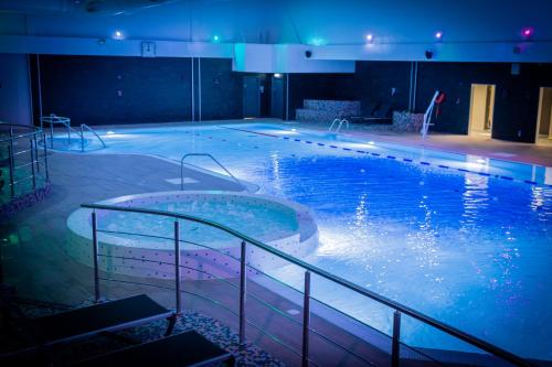 a large swimming pool with blue lights in a building at Village Hotel Cardiff in Cardiff