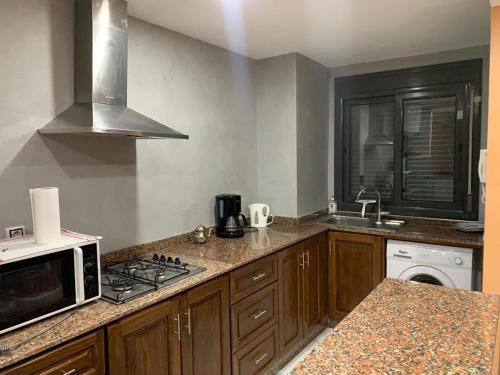 a kitchen with a stove top oven and a microwave at Laplaya Apppart Hotel in Tangier