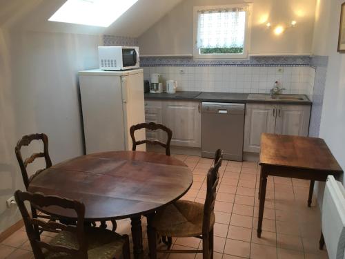 eine Küche mit einem Tisch, Stühlen und einer Mikrowelle in der Unterkunft LA POMMERAIE in Bosc-Bénard-Commin