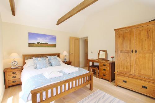 a bedroom with a large bed and a wooden cabinet at Heron's Hideaway in Wells next the Sea