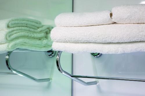 a stack of towels on a towel rack in a bathroom at Snoozebox Olympic Park in London