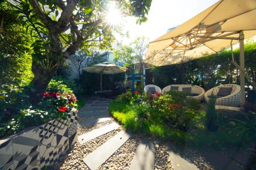 a patio with chairs and an umbrella and flowers at Alagon Saigon Hotel & Spa in Ho Chi Minh City